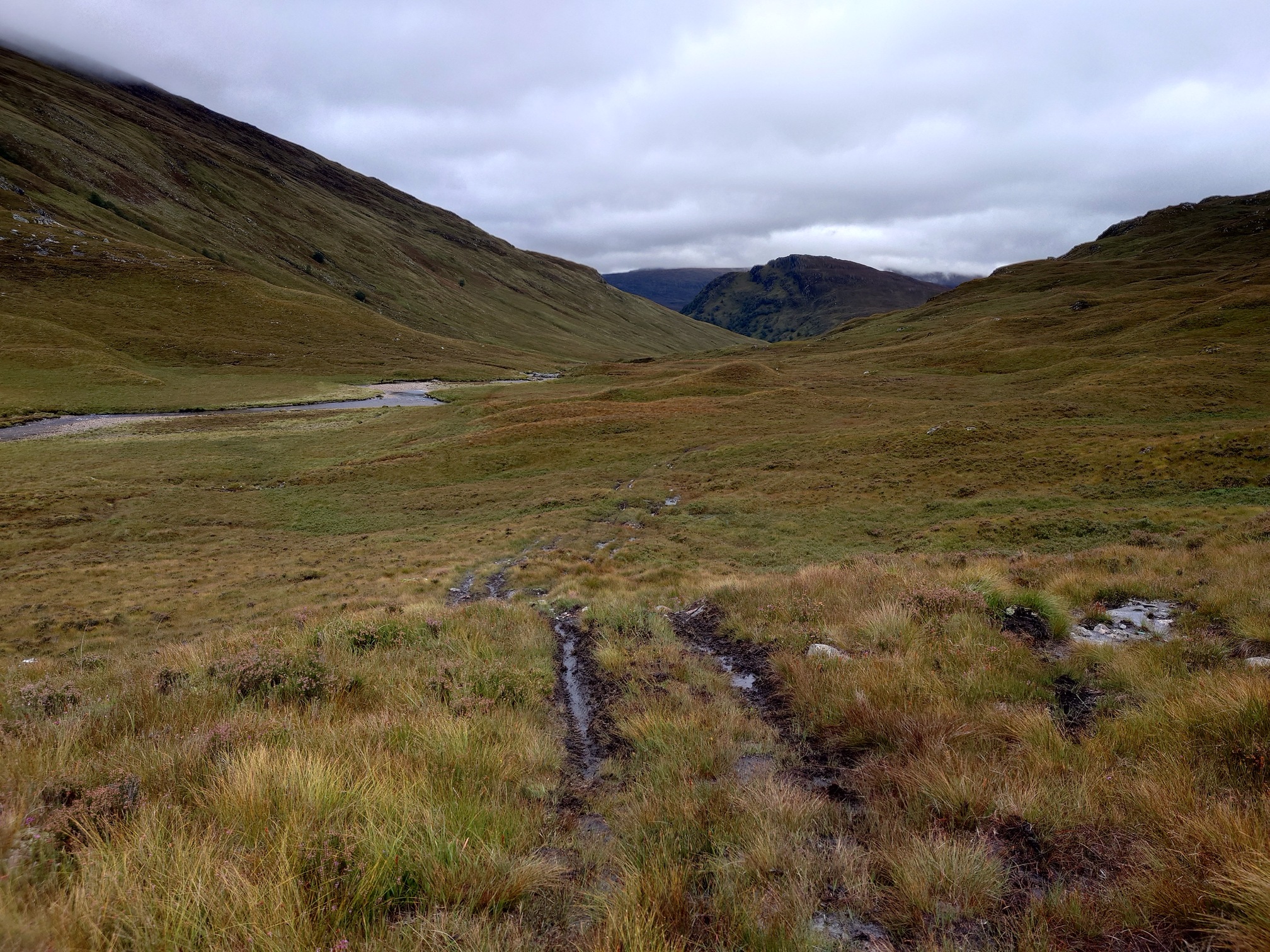 Muddy quadbike tracks show the way along the boggy valley bottom.