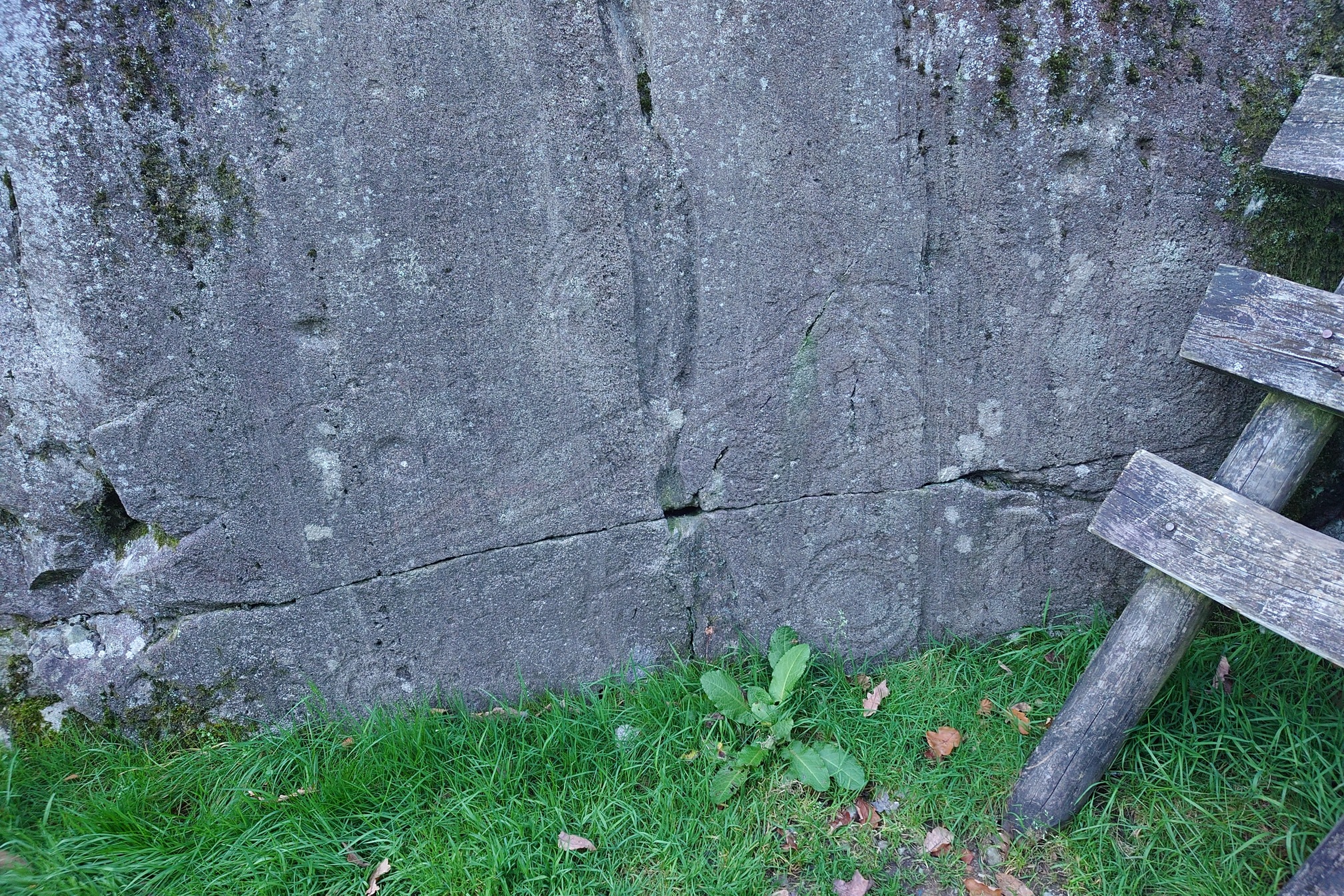 Faintly in the rock, we can see lines and concentric circles carved into the rock near the base