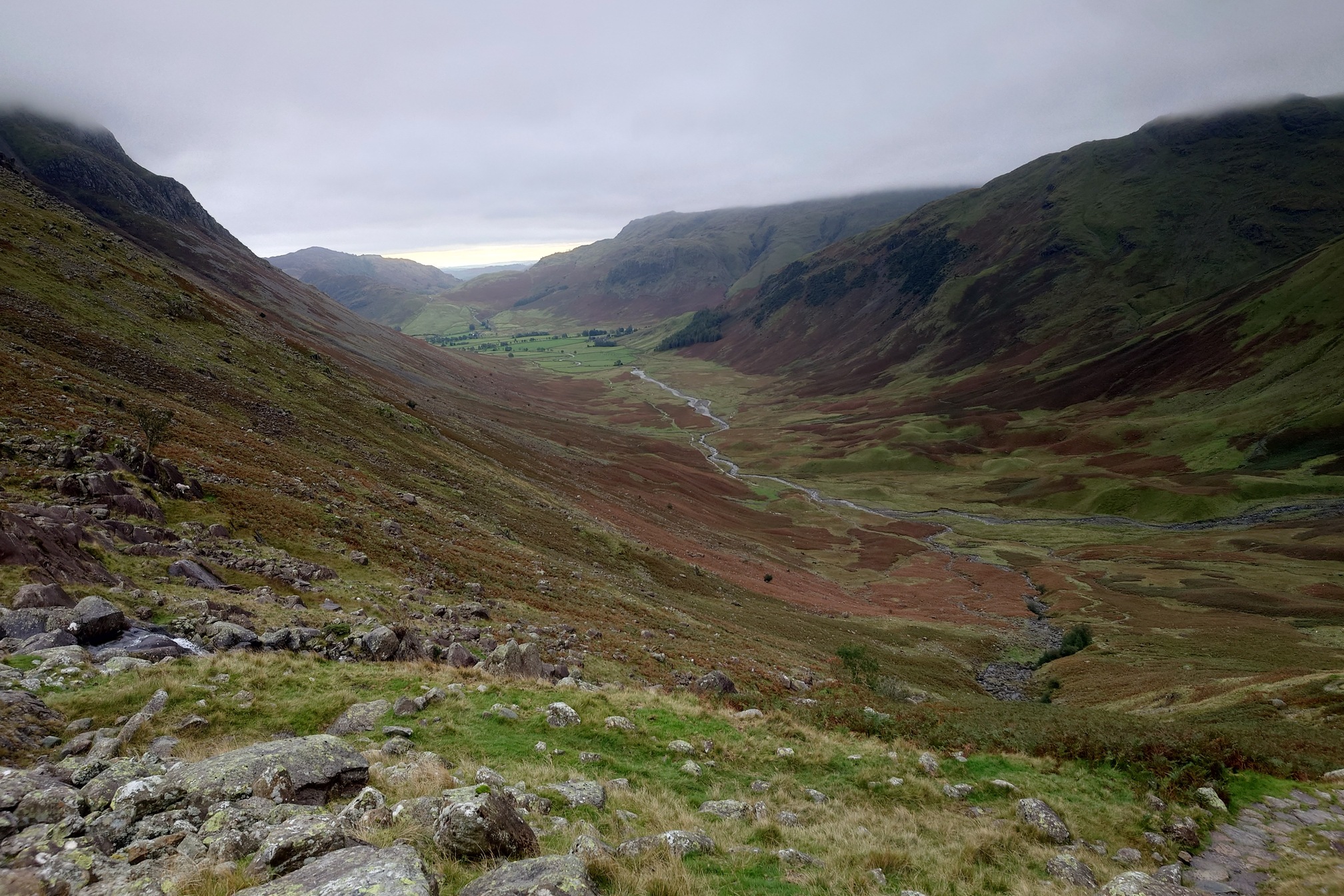 Looking down from near the top of teh pass at the magnificent U shaped valley, brown on the slopes with bracken and grassy on the valley floor with a stream wandering along