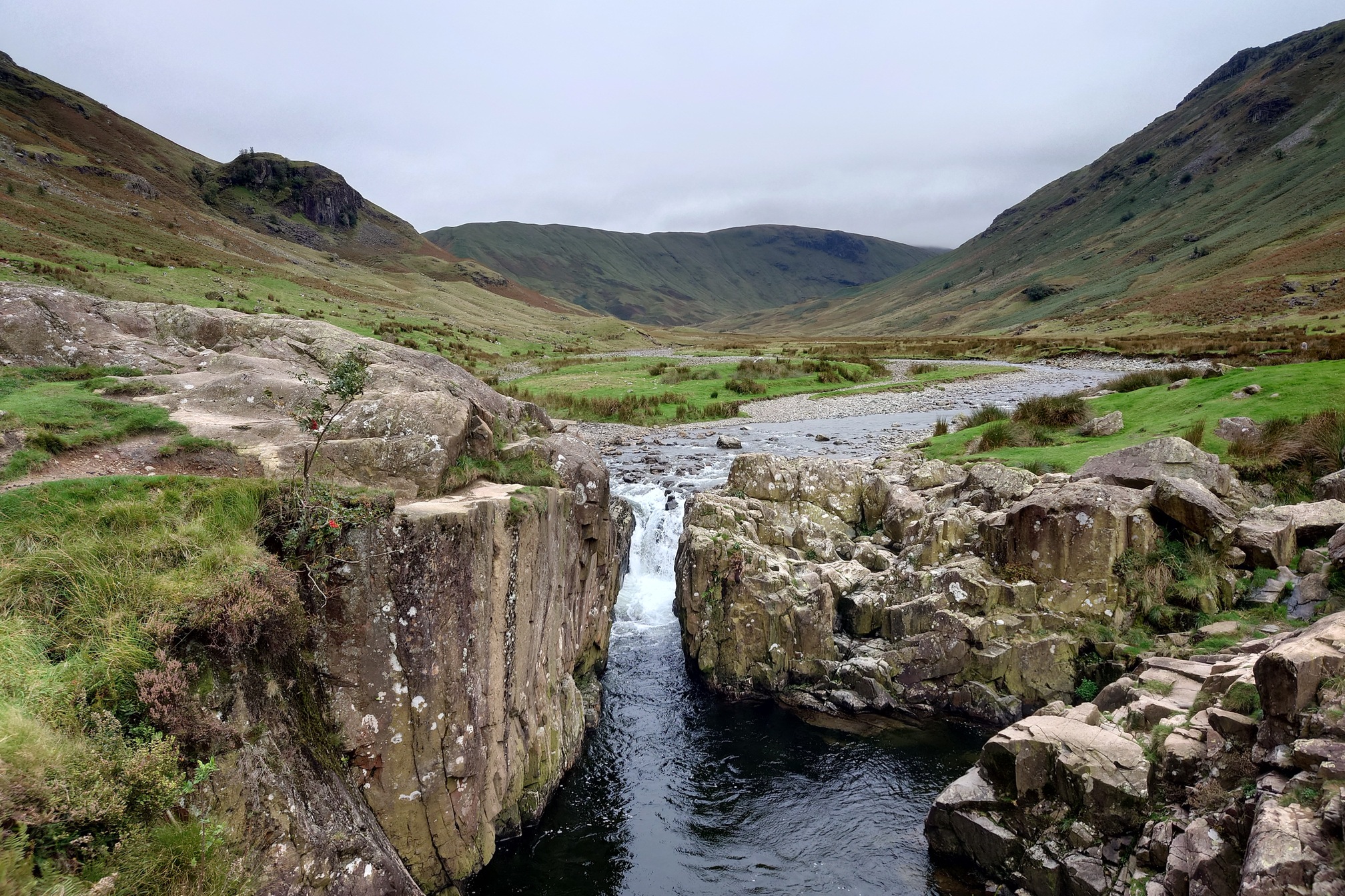 A larger waterfall cascades over rocks