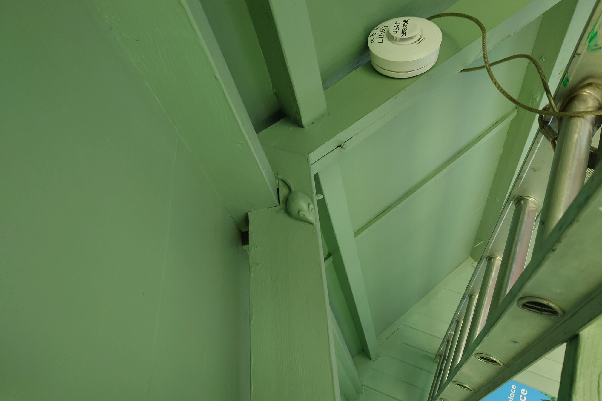 In the pale green rafters, a little wooden model of a mouse has been carved