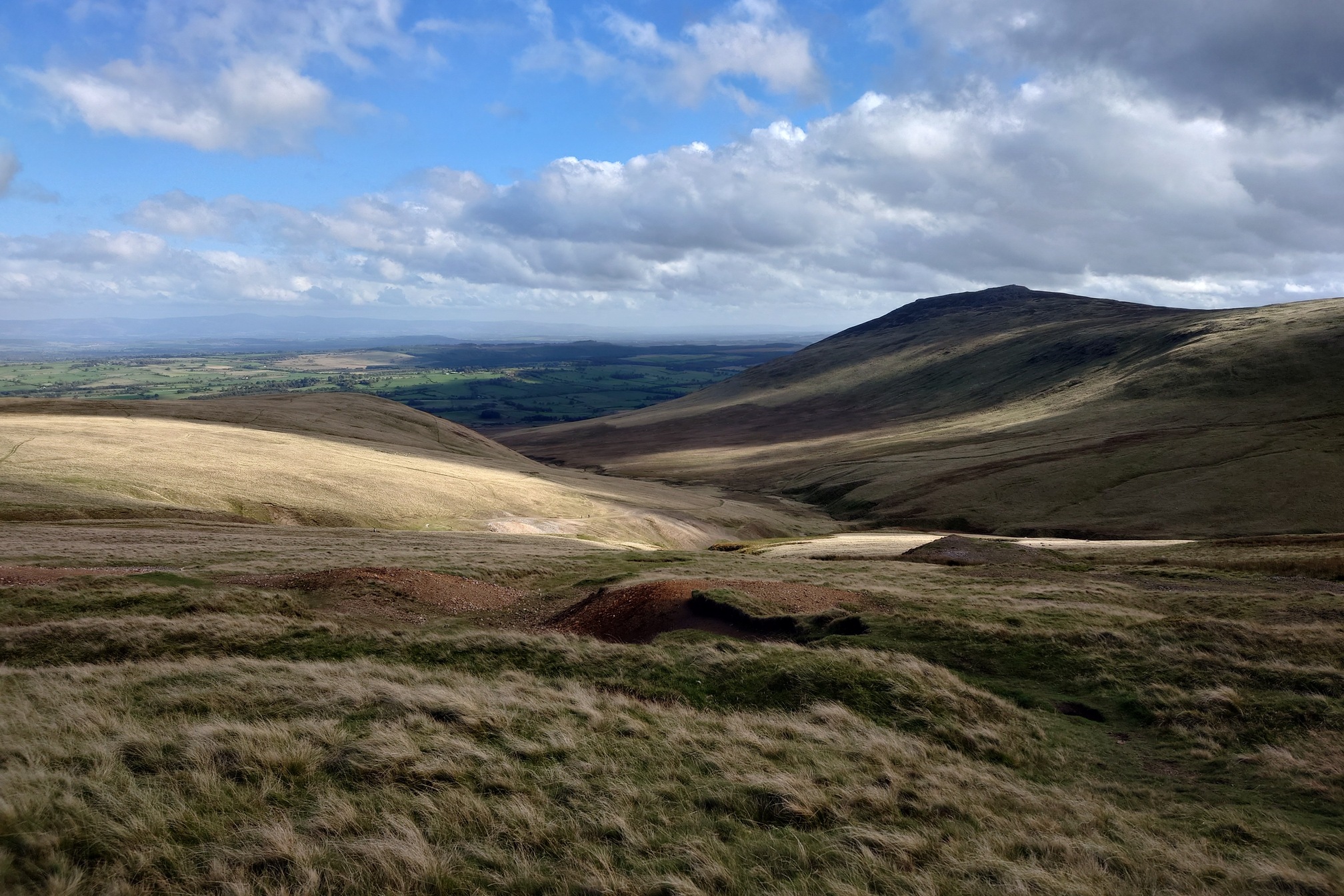 A view over the hills, gently sloping here but vast, with patches of sunlight