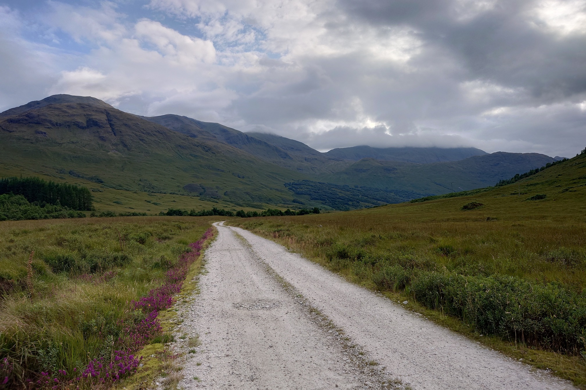 A broad gravel road stretches ahead down the valley, with mountains either side