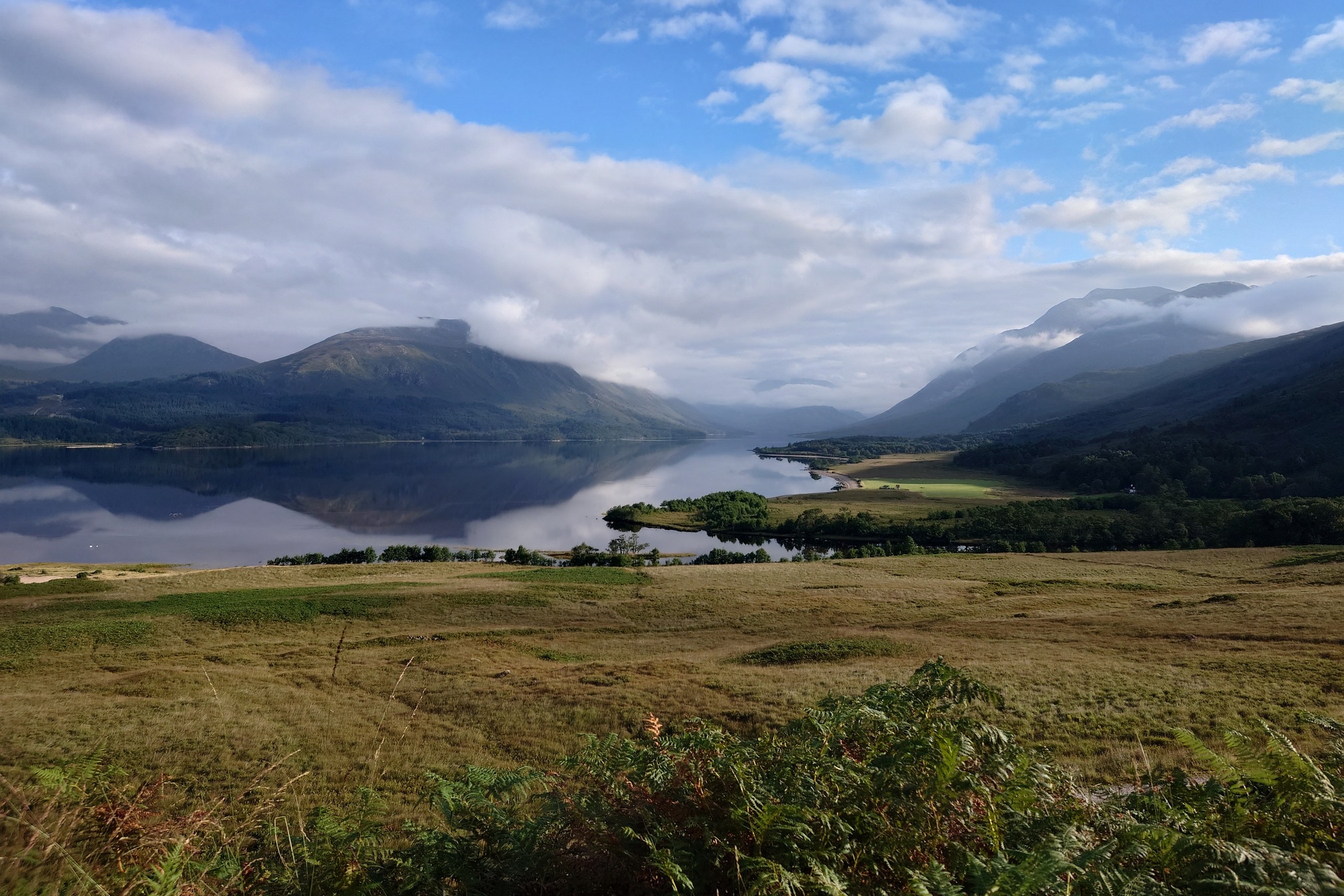 Looking up Loch Etive, the flat calm loch surrounded by mountains that disappear into low cloud further up the loch