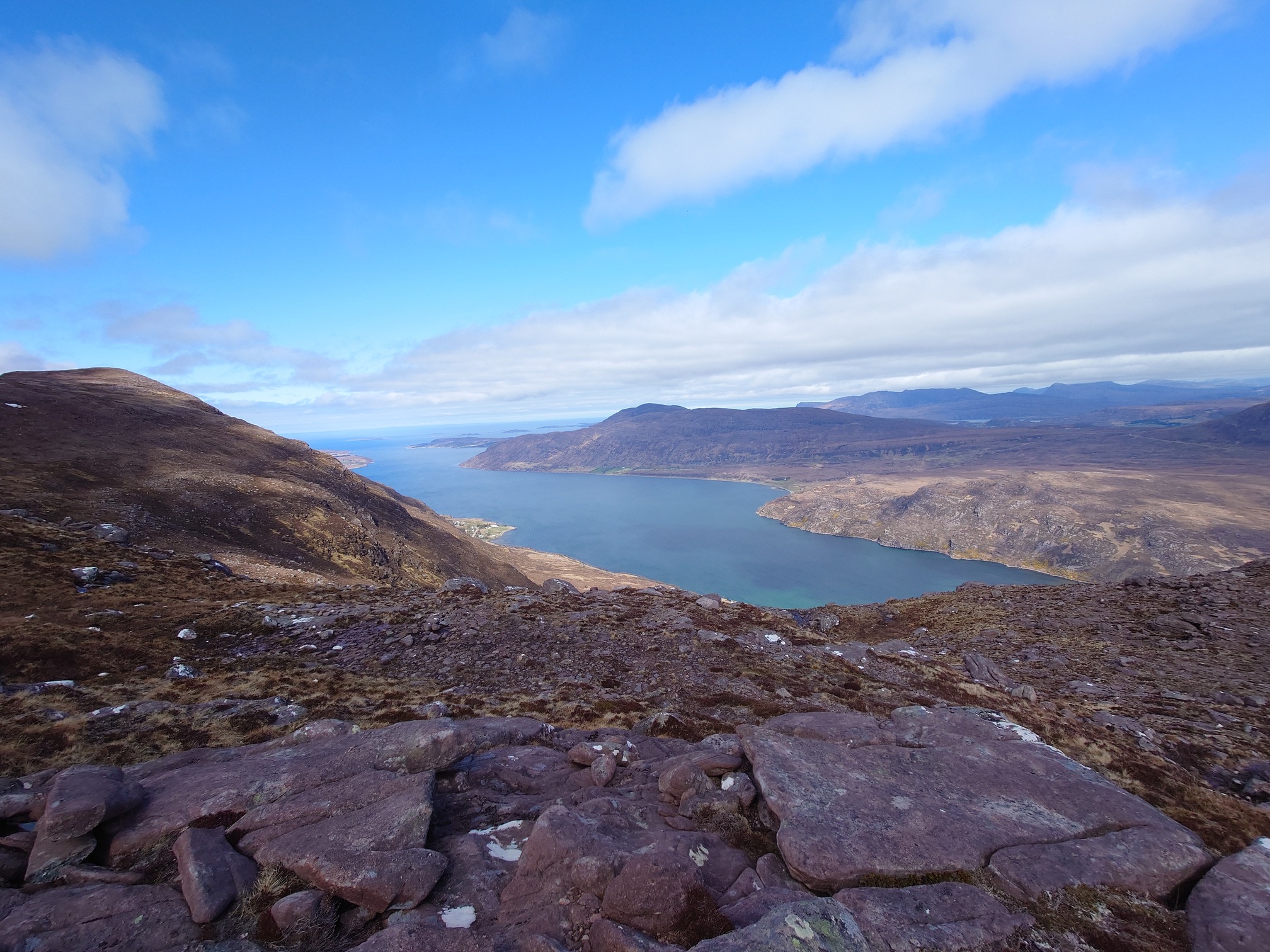 A view from several hundred metres above sea level of Little Loch Broom, sitting blue and bordered by spectacular mountain landscape